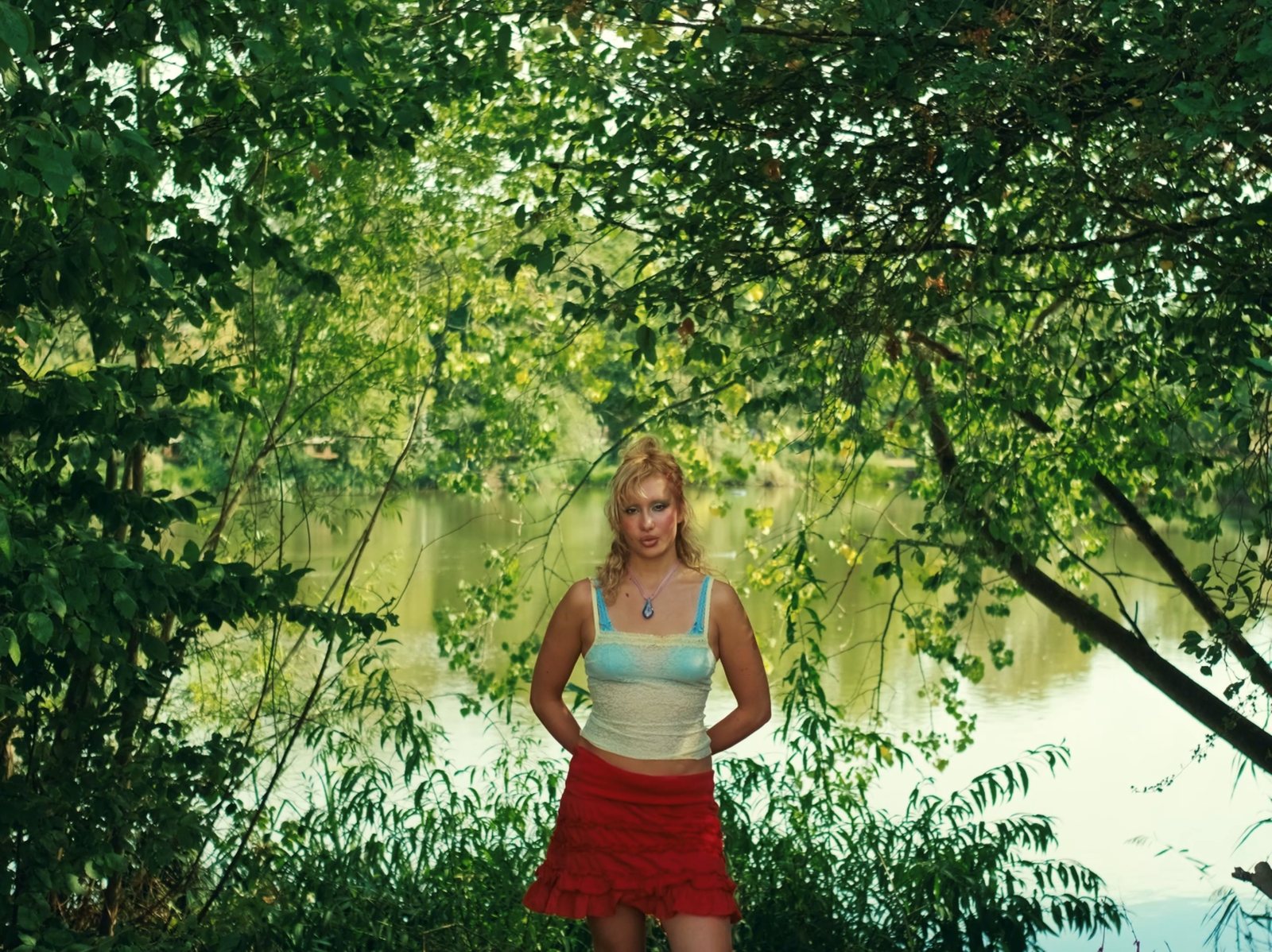 Still from the social campaign films for Azul by Luna Jones — Luna Jones standing by a river framed by overhanging trees