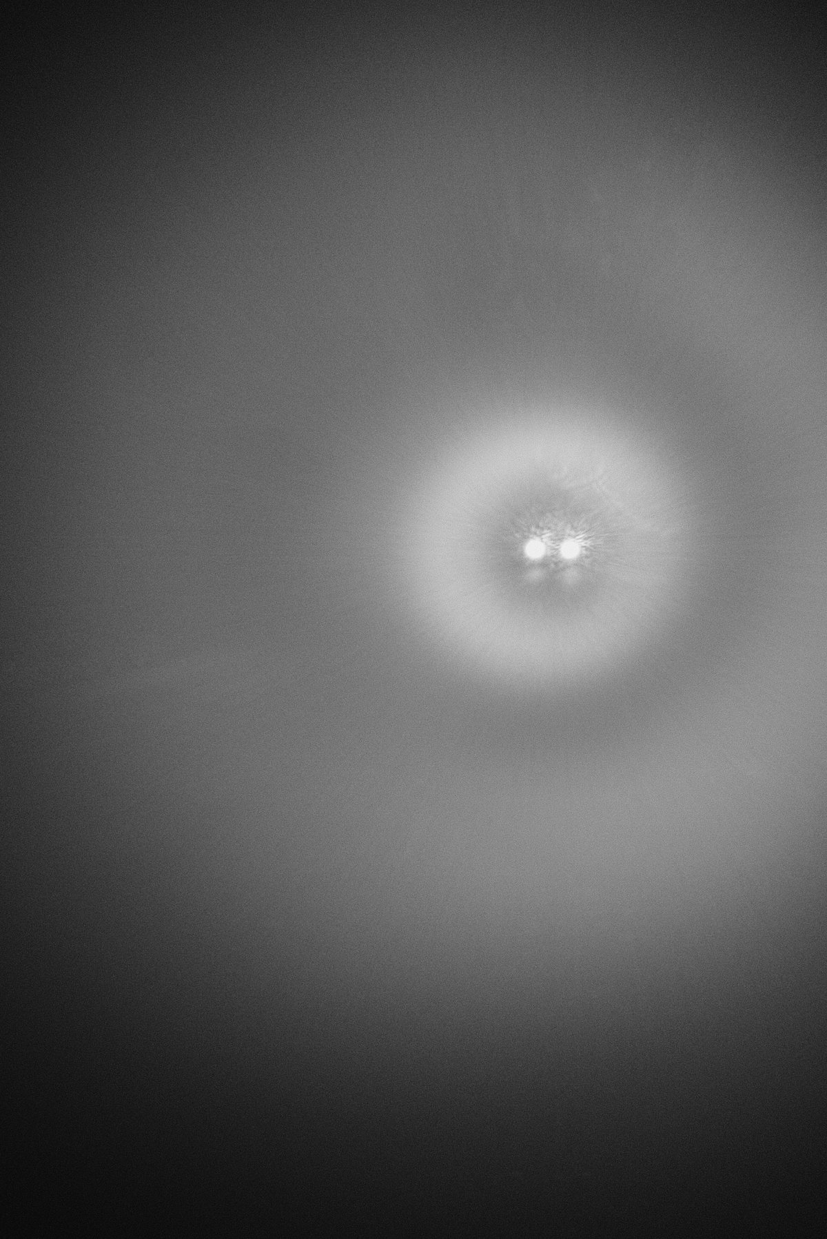Abstract black and white photo of two blurred lights glowing in fog