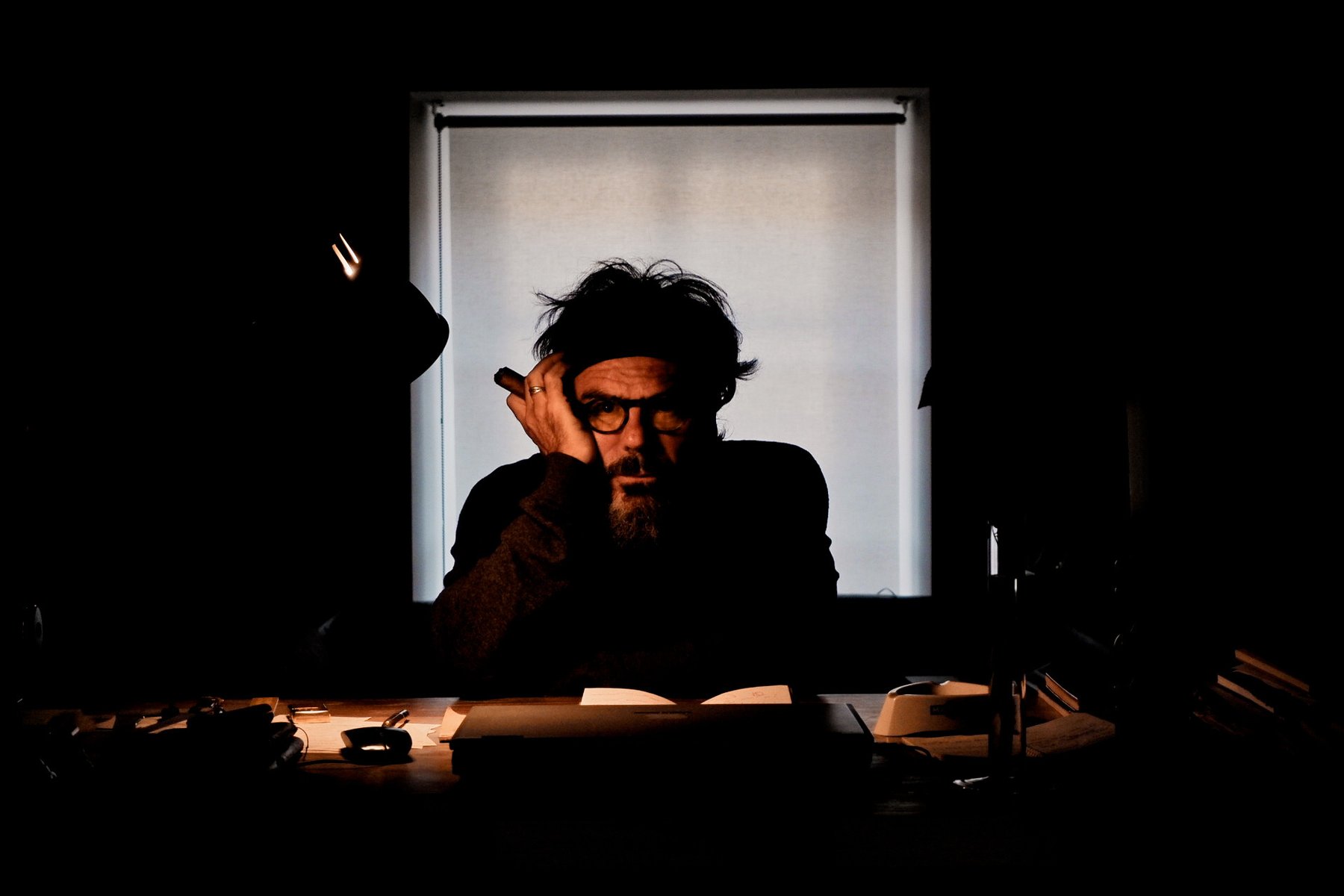 Backlit portrait of a man with a cigar and glasses, dramatic lighting